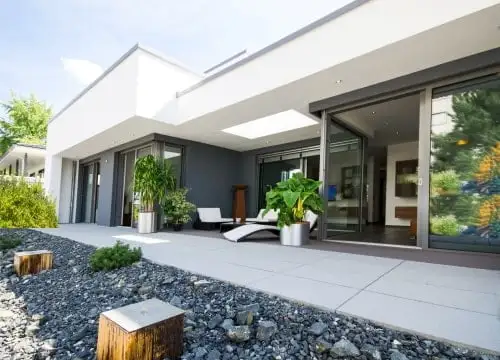 Terrasse mit grauen Terrassenplatten vor einem Haus mit weißer Fassade