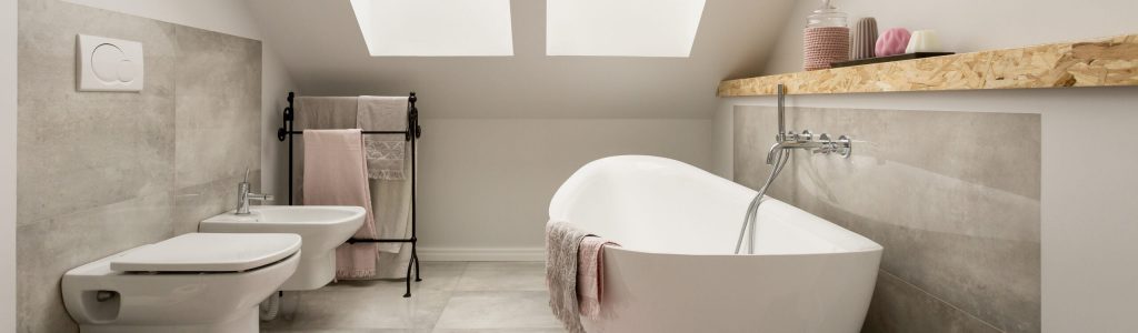 Romantic bathroom in a cosy attic Gefliestes Badezimmer im Dachgeschoss mit freistehenden Badewanne und einer Toilette